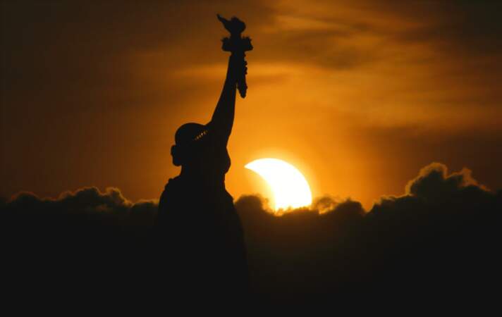 Le soleil se lève pendant l'éclipse solaire partielle, à côté de la statue de la Liberté à New York 